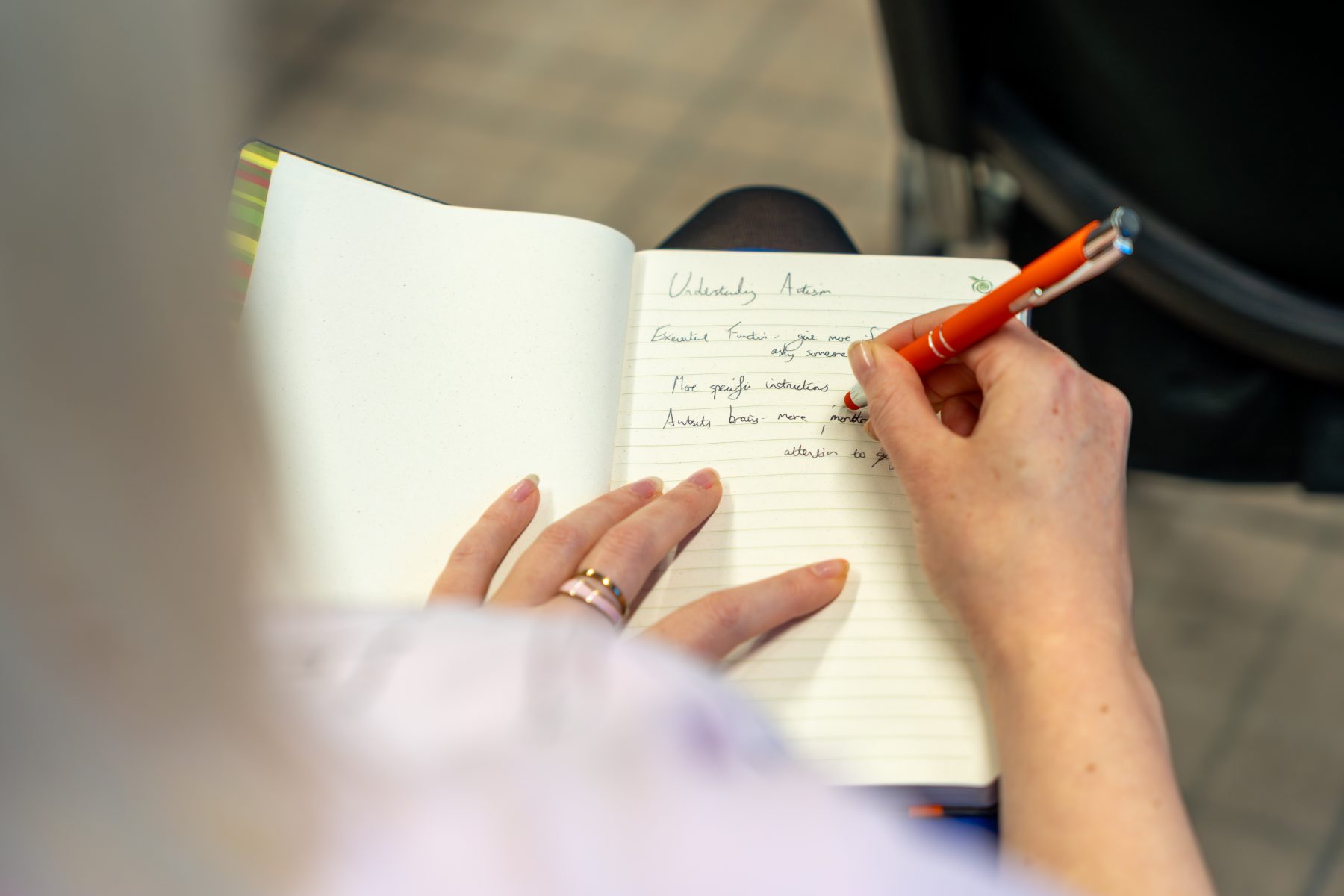 Over-the-shoulder shot of a woman taking notes during a neurodiversity training session
